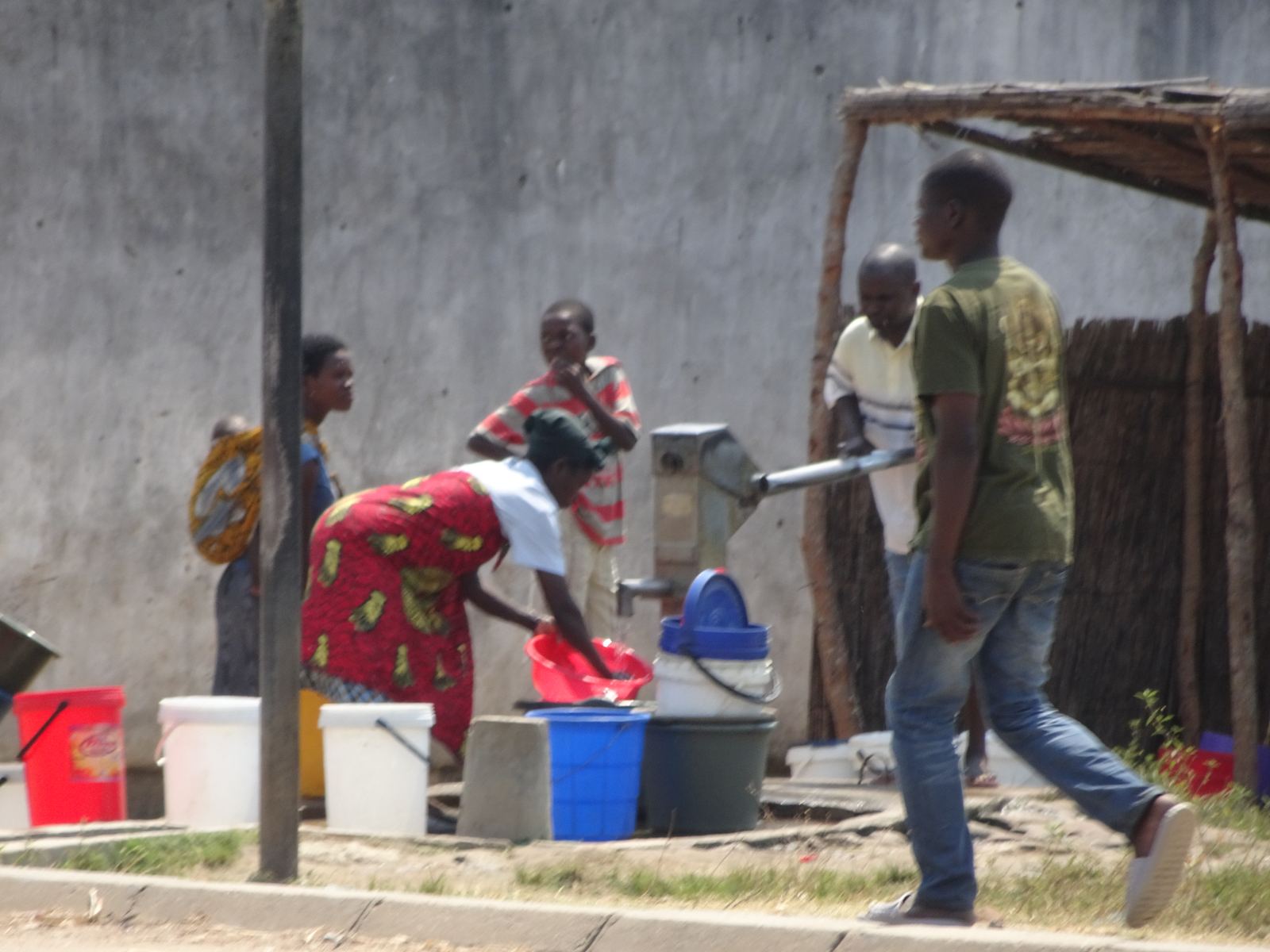 Mensen vullen emmers bij een handwaterpomp in Malawi